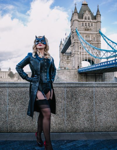 Woman in cat costume posing confidently near Tower Bridge, London.