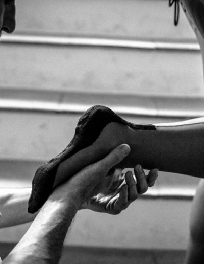 A man holds a woman's foot dressed in black stockings, showcasing an intimate and artistic moment on stairs.
